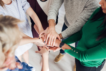 High angle shot of a group of colleagues standing in a circle with their hands in a huddle