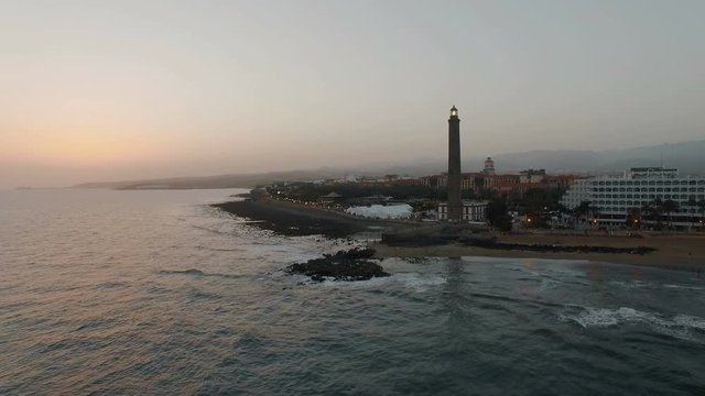 Aerial evening scene of resort on the coast with lighthouse. Maspalomas, Gran Canaria