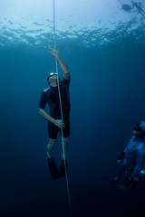 Free diver ascending along the rope in the depth