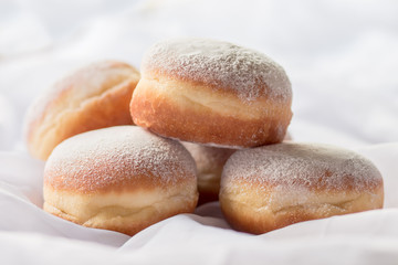 Jelly filled doughnuts with powdered sugar on a bed with white sheets