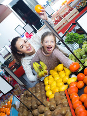 Smiling mother and daughter buying ripe fruits