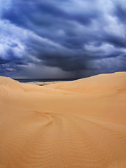 Sand dune dark clouds sea