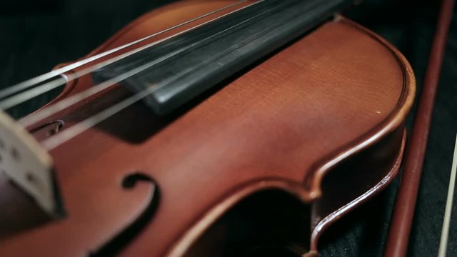 close up dolly shot of part of aged violin on black background