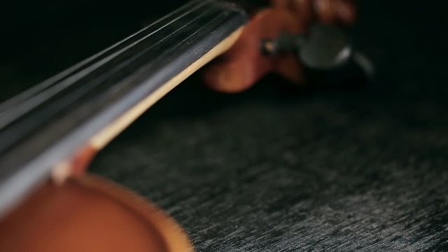 close up refocusing shot of part of aged violin on black background