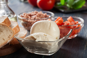 Ingredients ready for preparing bruschetta with tuna, mozzarella cheese and tomatoes