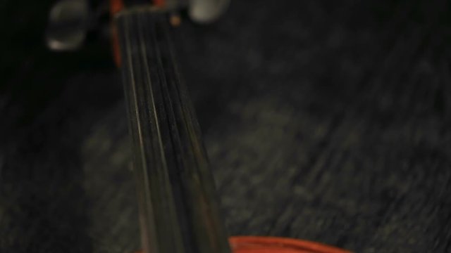 close up refocusing shot of part of aged violin on black background