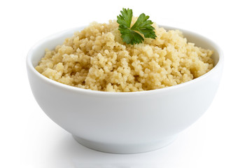 Cooked couscous with green parsley in white ceramic bowl isolated on white.