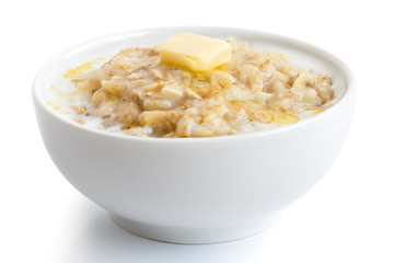 Cooked whole porridge oats with milk and butter in white ceramic bowl isolated on white. - obrazy, fototapety, plakaty