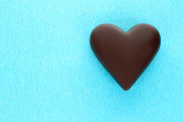 Black chocolate heart on blue background