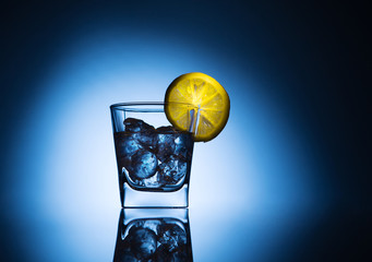 Transparent glass of water and ice on a dark background on a glass of fresh lemon on the table beautiful reflection.