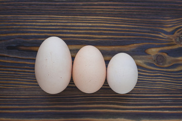 Three different eggs laying on the wooden background can show you that size matters