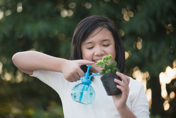 Asian girl watering a red flower in the garden