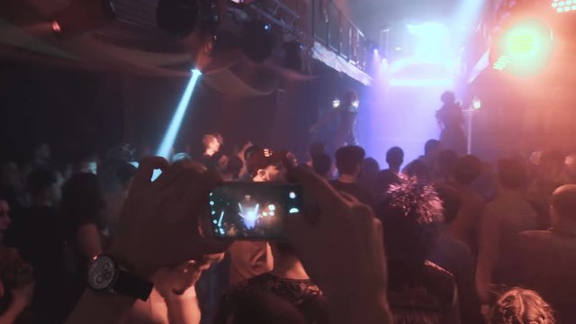 People taking photos or recording video with their smart phones at music concert. Night party, night rave.