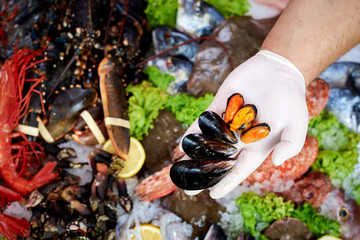 Seller presenting fresh mussels in fish store
