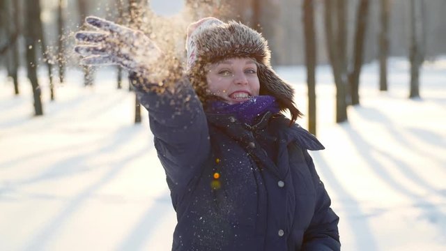 Sunny winter time, beautiful woman throwing a snowballs. Happiness and joyful, fun and smiling