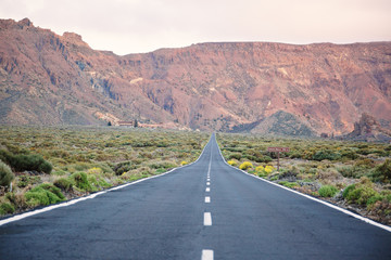Scenic landscape of long straight road leading to mountains on Tenerife Island