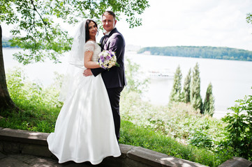 Loving wedding couple hugging backgroun landscape with lake.