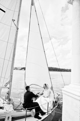 Fototapeta premium Wedding couple in love at small sailboat yacht on lake. Black and white photo.