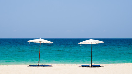 White beach umbrella on a sunny day against sea background.