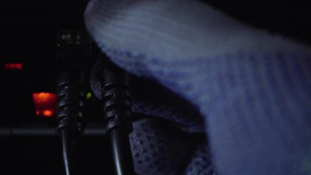 Malefactor hands in gloves disconnect the cable from the Internet router, server, database