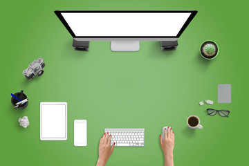 Top view of studio desk with modern devices. Computer display, tablet and mobile phone. Green desk...