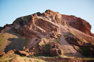 Graphic landscape shot of one red rocky mountain with blue sky above