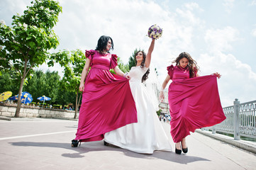 Bride walking and having fun with charming bridesmaids on rose dresses.