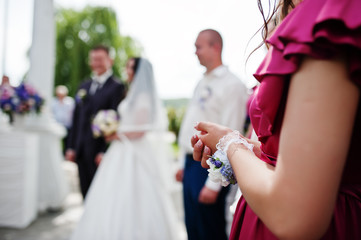 Hands of bridesmaid against wedding couple on wedding ceremony.