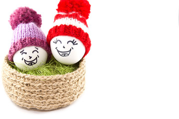 Easter eggs in a basket. Emoticons in knitted hats with pom-poms. Knitted basket of jute, sisal green. Handmade.