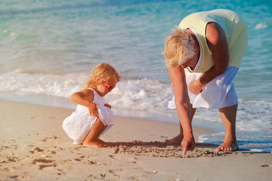 grandmother with little granddaughter play at beach