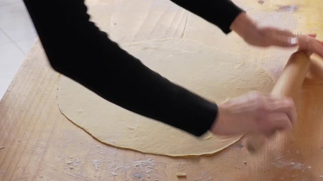 woman hands passing a rolling pin on fresh dough