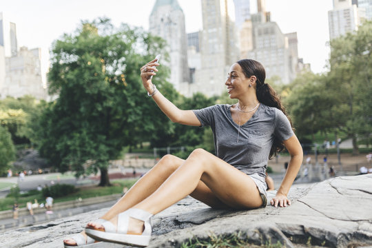 USA, Manhattan, smiling young woman taking selfie with smartphone in Central Park