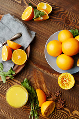 Rustic wooden kitchen table with fruits and spices laid out on it, all set for squeezing fresh juice: delicious ripe oranges cut in half, mint and star anise scattered in elegant assortment