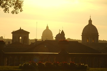 Beautiful sunset view of the roofs and domes of Rome with lens flare