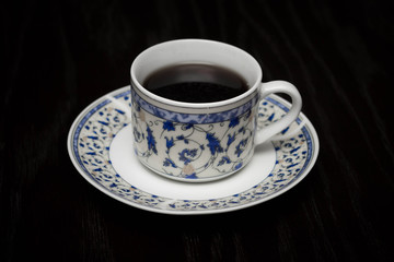 A cup of hot caefee standing on the wooden table.