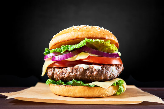 Craft beef burger on wooden table isolated on black background.
