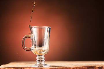 Brown splashes out drink from cup of tea on a brown background