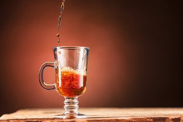 Brown splashes out drink from cup of tea on a brown background
