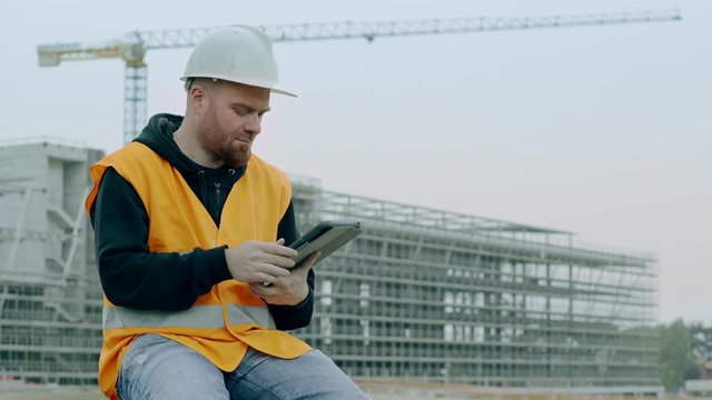 young foreman sitting in construction site use the tablet