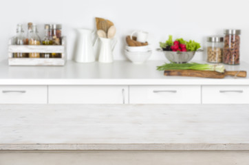 Fototapeta na wymiar Wooden table on blurred kitchen interior background with fresh vegetables