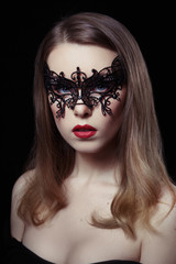 Beauty portrait of sexy mysterious woman in lace mask on a black background.