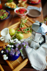 High angle view of beautifully decorated wooden tray with metallic teapot, fresh-cut field flowers and green garden apples