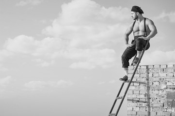 Fototapeta premium Retro construction worker climbing a ladder while working on the