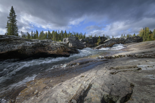 Beautiful rocky waterfall in sweden in magic pine forest landscape