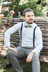 Obraz premium Handsome young man sitting on a bench smiling in the park