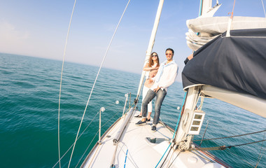 Young couple in love on sail boat having fun with champagne flute glasses - Happy exclusive travel concept on sailboat tour - Boyfriend and girlfriend on luxury cruise - Sunny afternoon color tones
