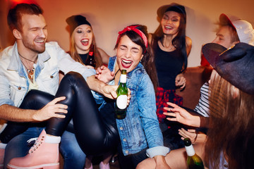 Group of trendy young people getting drunk at late night swag party, going crazy and laughing while...