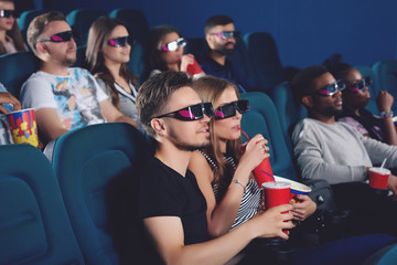 Couple wearing in 3d glasses in modern cinema hall.