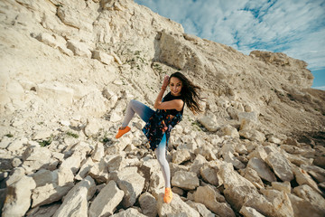 Young woman posing and dancing near the beautiful mountains dressed colorful clothes