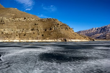 замерзшее озеро в горном ущелье, весна, горные склоны, природа Северного Кавказа, красивый пейзаж